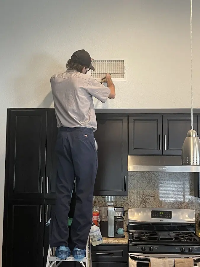 Technician inspecting an air vent during HVAC service in Plaistow
